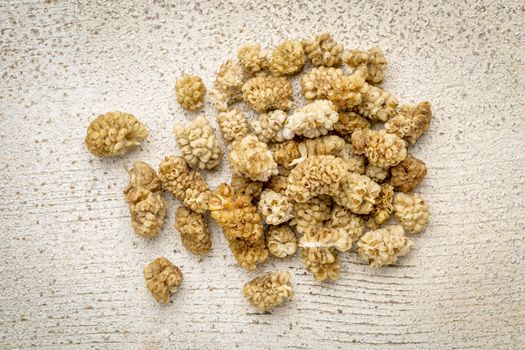 a pile of dried white mulberry fruit against rustic barn wood