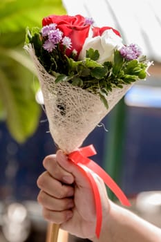 Hand holding bouquet of roses.