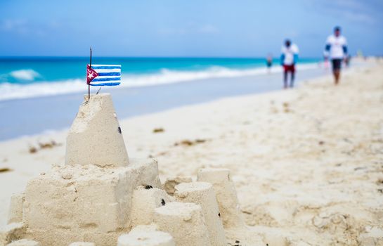 Cuban Sandcastle with the country Flag on one of the most Beautiful Beach of Cuba with tourists in background