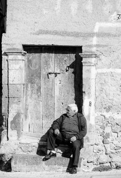LEONFORTE, ITALY - JANUARY, 08: Old man sitting on the step of old door on January 08, 2014