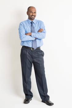 Full body Indian businessman arms crossed standing on plain background with shadow 