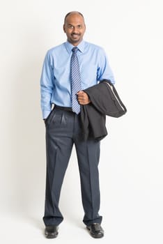 Full length Indian businessman looking at camera, on plain background.