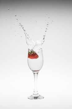 fresh strawberry dropped into water with splash on white backgrounds