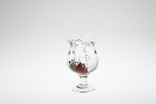 Close-up image of strawberry dropped to water on white background