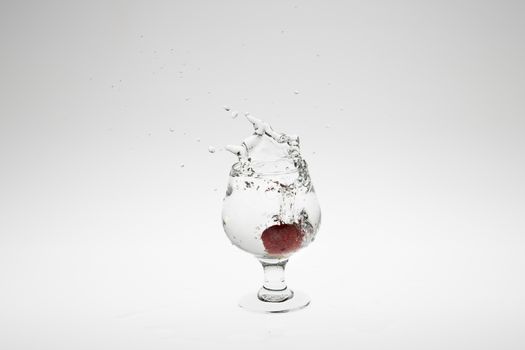 Close-up image of strawberry dropped to water on white background