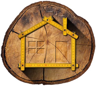 Wooden house project concept. Wooden meter ruler in the shape of house in a section of tree trunk isolated on white background
