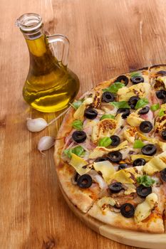 Fresh delicious pizza, extra virgin olive oil and garlic on wooden background. Pizza eating background. 