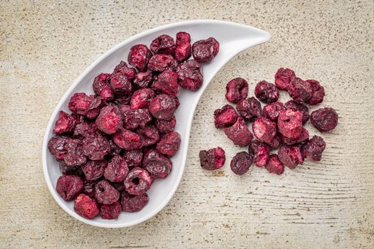 Freeze dried cherries in a teardrop bowl against rustic barn wood.