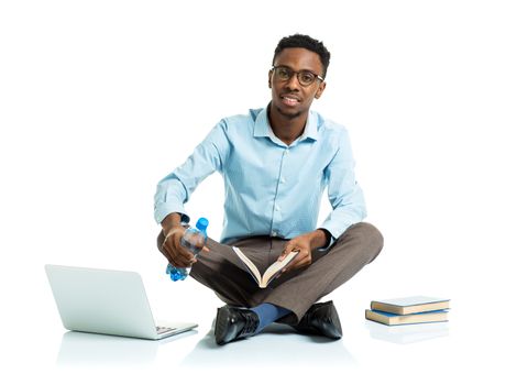 Happy african american college student sitting with laptop on white background
