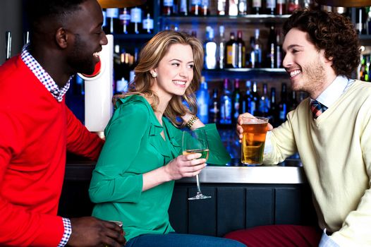 Group of three friends in a bar having drinks