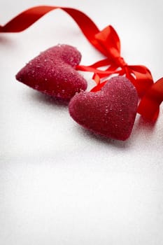 Red hearts tied with a ribbon on a silver background.