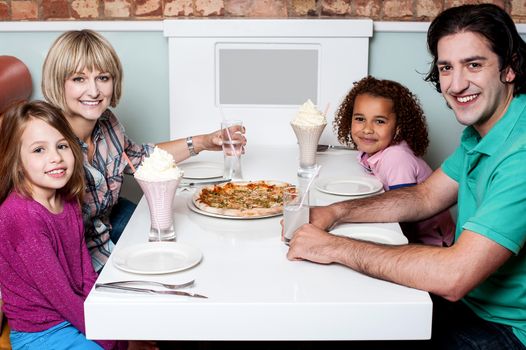 Happy couple and their children sitting in restaurant
