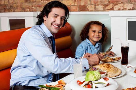 Happy father and daughter eating in a restaurant