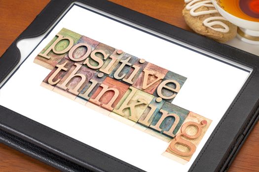 positive thinking typography - isolated text in letterpress wood type blocks on a digital tablet with a cup of tea