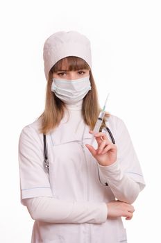 Portrait of medical worker in a white coat, hat, gloves and a mask, with a syringe and vial in hands