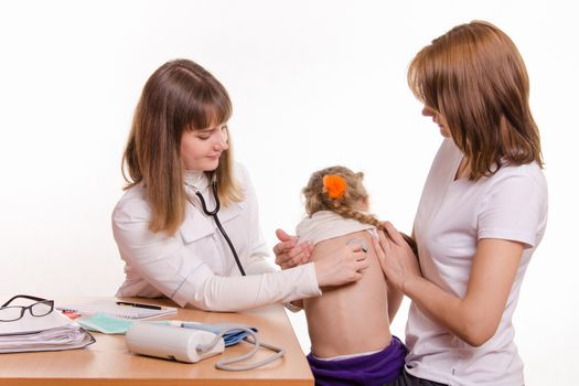 Doctor pediatrician examines a sick child at home