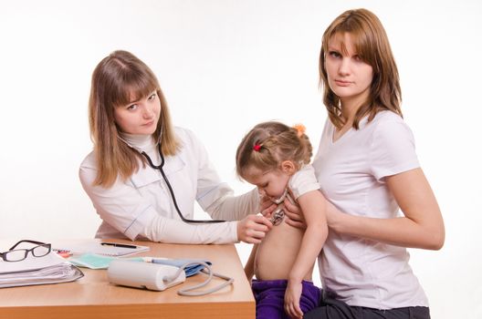 Doctor pediatrician examines a sick child at home