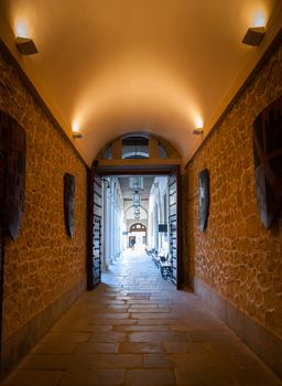 A lighted hallway leads to the courtyard of a Spanish Castle.