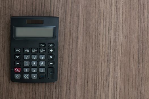 Overhead view of a calculator on a wood desk