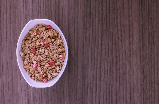 A small dish of granola over wood 