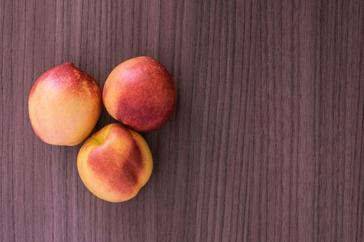 Three succulent red and yellow peaches over wood 