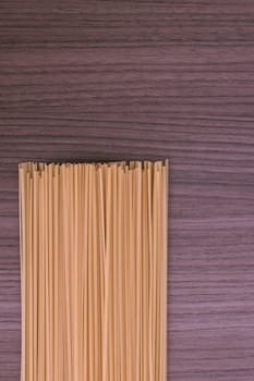 Some dry spaghetti over wood background (vertical)