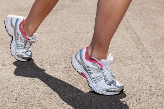 Woman legs in sneakers on asphalt background