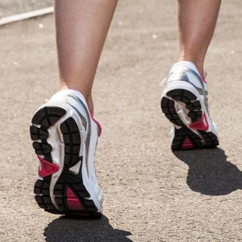 Woman legs in sneakers on asphalt background