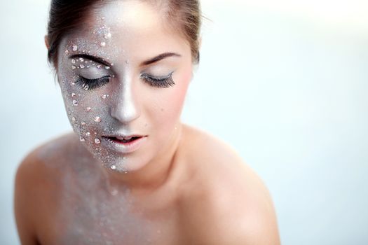 Portrait of a beautiful girl with silver body art over a white background