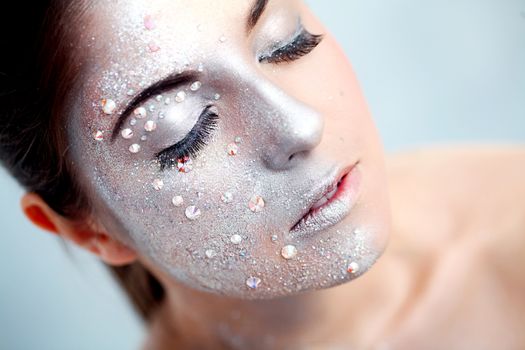 Portrait of a beautiful girl with silver body art over a white background