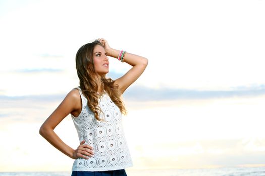 Portrait of a beautiful girl with brown hair who is posing over a sky background