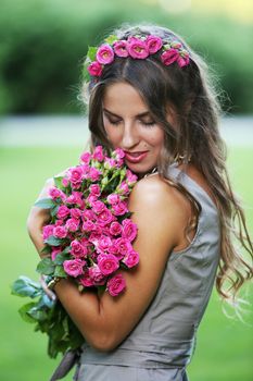 Portrait of a beautiful girl holding bouquet of flowers in the park