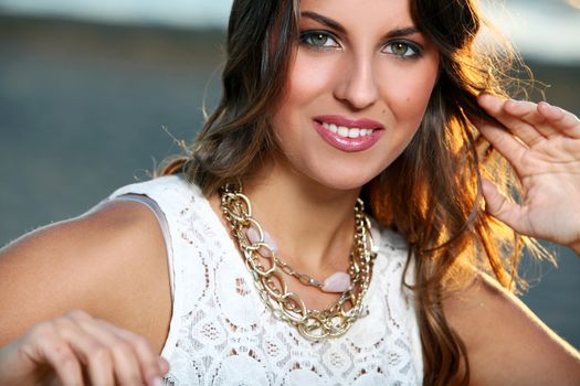 Portrait of a beautiful girl with brown hair who is posing over a sky background