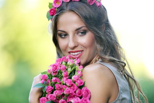 Portrait of a beautiful girl holding bouquet of flowers in the park