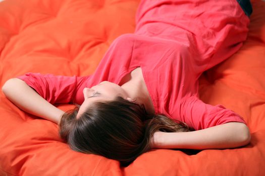 Sensual young woman dreaming on an orange blanket