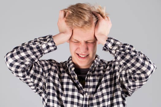 Young handsome guy with hand on head over grey background