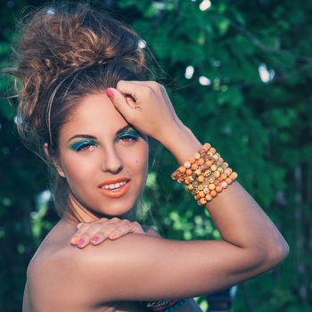 A portrait of a girl posing with beautiful artistic makeup and colorful handmade bracelets