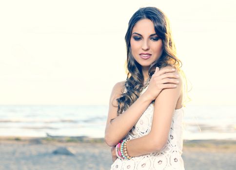 Portrait of a beautiful girl with curly hair and white dress who is posing outdoors