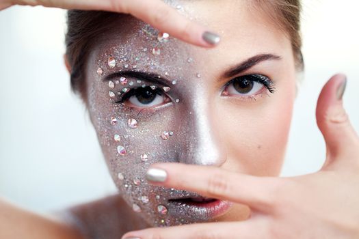 Portrait of a beautiful girl with silver body art over a white background