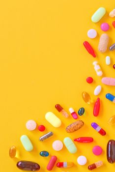 Many colorful pills isolated on yellow background