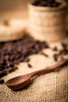 pile of coffee beans and wooden spoon with space for text, focus to spoon with shallow focus