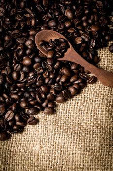 pile of fresh and bio aromatic coffee beans and wooden spoon with space for text