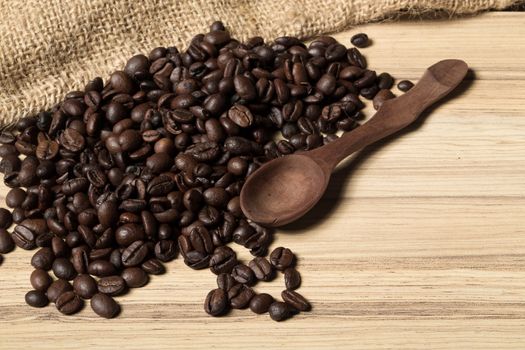 pile of fresh and bio aromatic coffee beans and wooden spoon