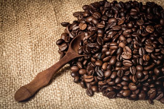 pile of fresh and bio aromatic coffee beans and wooden spoon