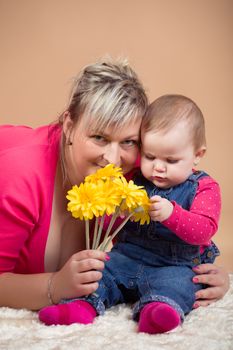 infant baby with his mom and yellow flowers- the first year of the new life