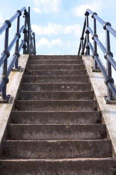 Flight of weathered concrete steps leads upwards into the blue sky