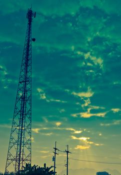 The Communication Antenna Tower and Cloudy Sky with Sunbeam in the Morning.