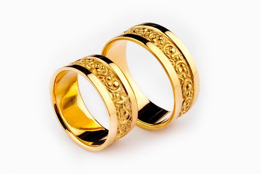 Pair of handcrafted gold wedding rings on white background