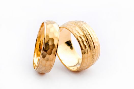 Pair of handcrafted gold wedding rings on white background