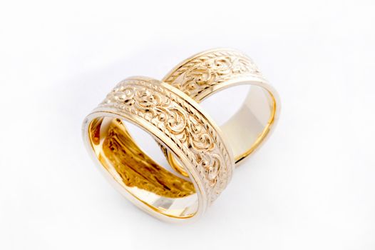 Pair of handcrafted gold wedding rings on white background